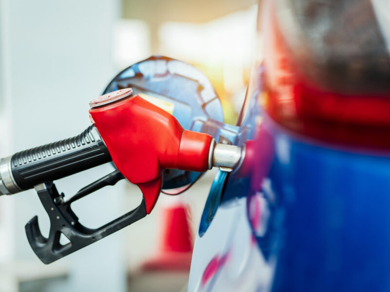Red fuel nozzle inserted into a blue vehicle at a fueling station