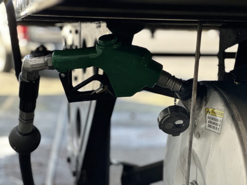 Green diesel nozzle filling off-road fuel tank labeled for ultra low sulfur diesel