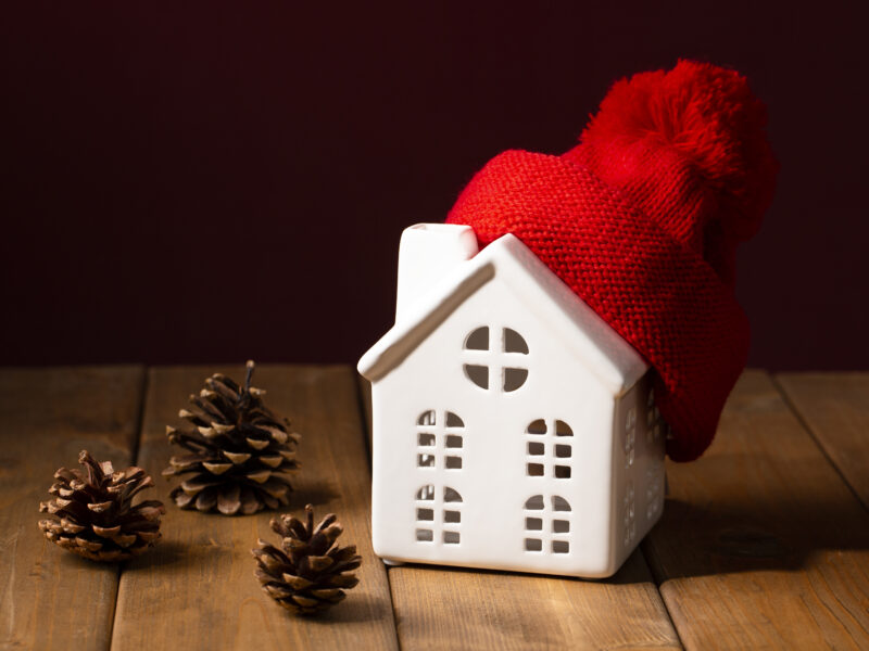 Ceramic house with red winter hat and pinecones