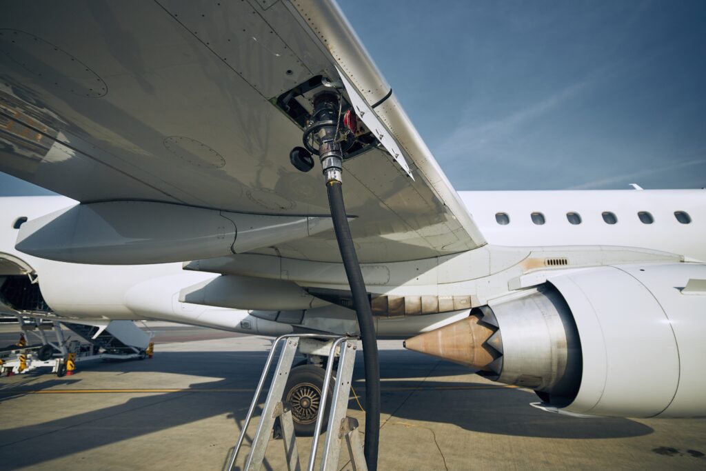 Close-up of Jet-A fuel delivery to a commercial airplane wing on the tarmac.