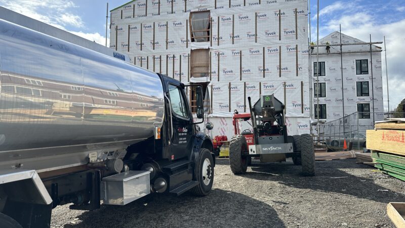Star Oilco fuel truck delivering diesel to construction site with Skyjack forklift and Tyvek-wrapped building