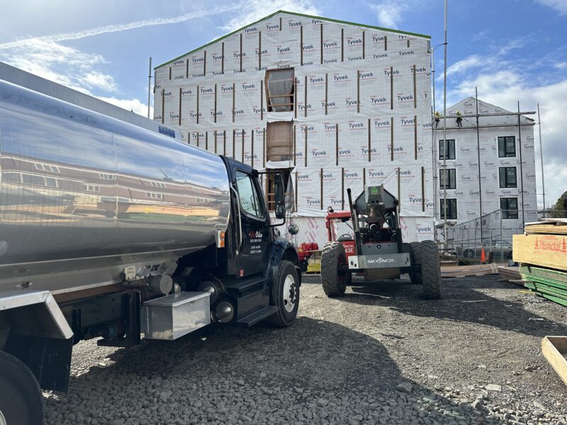 Star Oilco fuel truck delivering diesel to construction site with Skyjack forklift and Tyvek-wrapped building