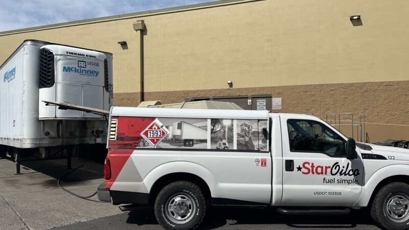 Star Oilco fuel service truck refueling a McKinney refrigerated trailer at a commercial loading dock