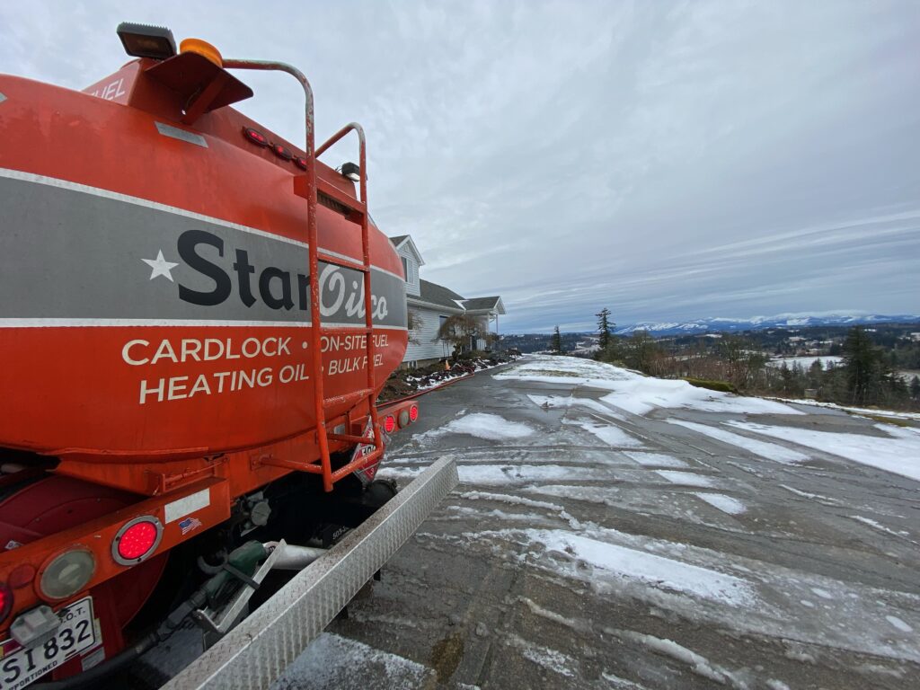 Star Oilco red heating oil delivery truck parked on a snowy hillside driveway overlooking the valley and mountains