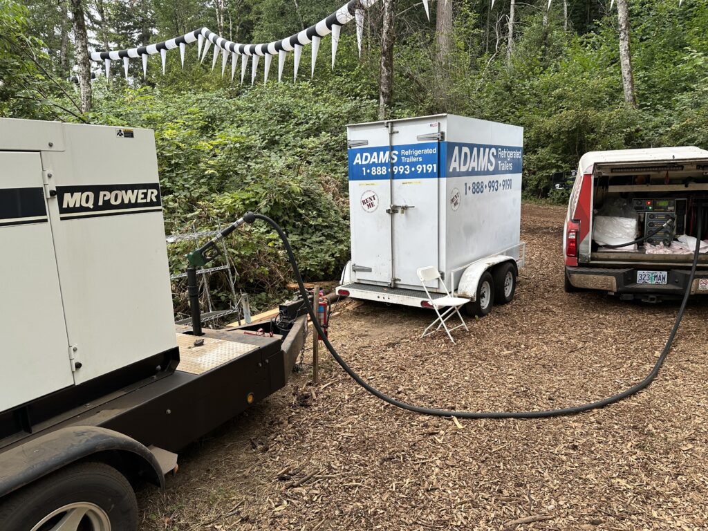 Star Oilco service truck refueling an MQ Power generator and Adams refrigerated trailer at an outdoor event site