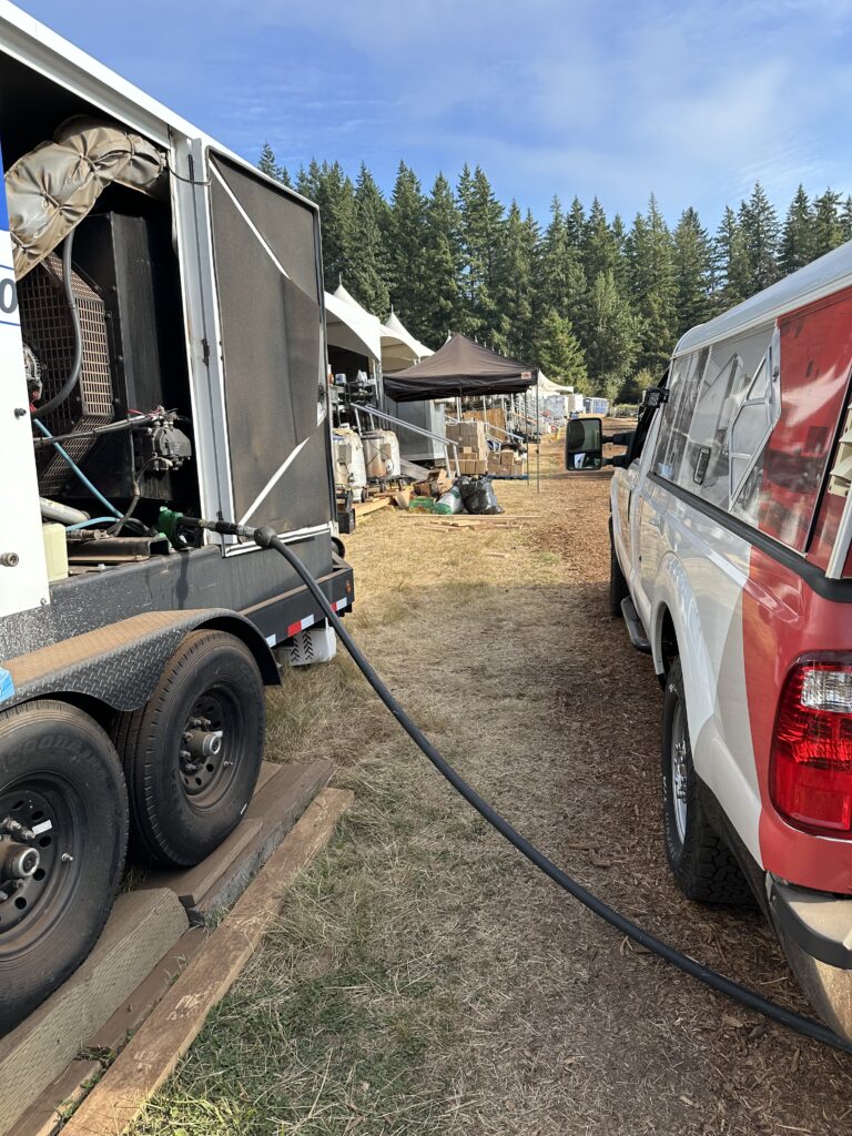 Star Oilco service truck refueling a large generator at an outdoor festival site with tents and equipment