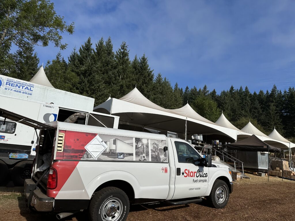 Star Oilco service truck parked at an outdoor event site with large tents and rental equipment in the background